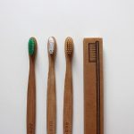 Trois brosses à dents en bambou et une boîte en carton sur fond blanc